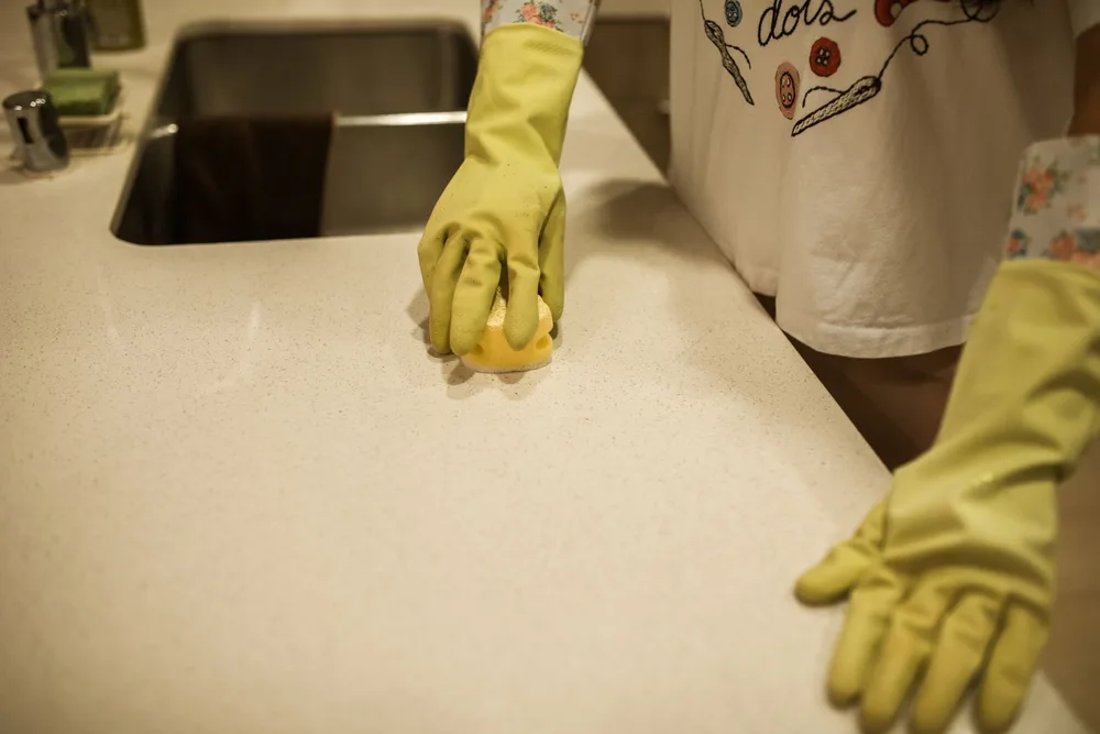 Hands in protective gloves carefully wiping a kitchen countertop